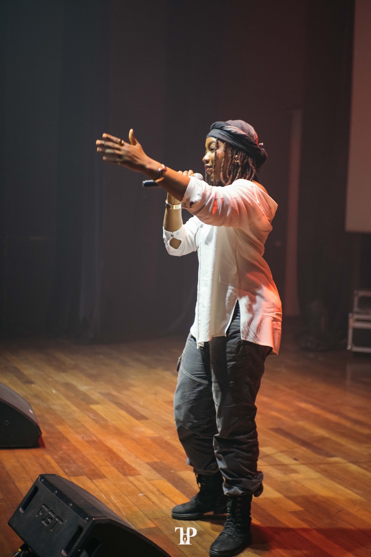 A spoken-word artist performing on a dark theatre stage